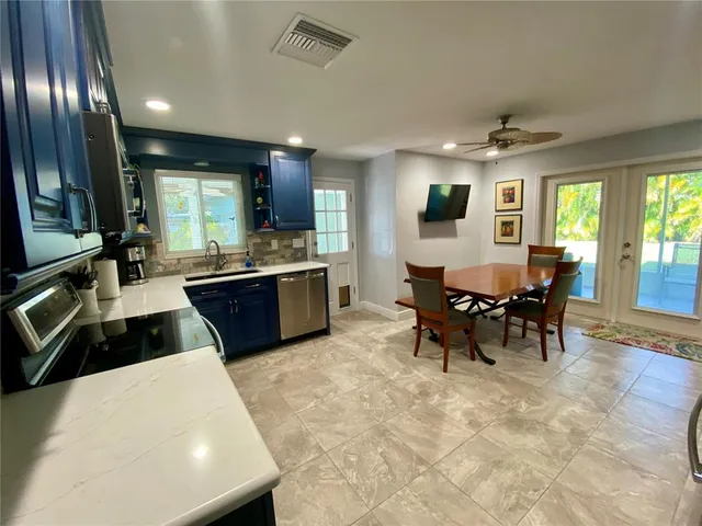 a kitchen with stainless steel appliances kitchen island granite countertop a sink a stove a microwave a dining table and chairs with wooden floor