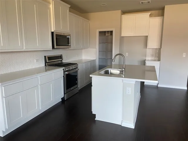 a kitchen with stainless steel appliances granite countertop a sink a stove top oven a counter space and cabinets