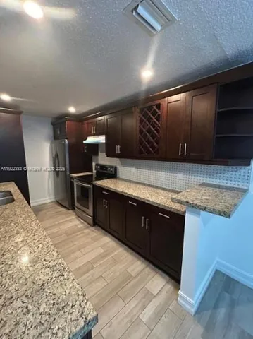 a large kitchen with wooden floors and stainless steel appliances