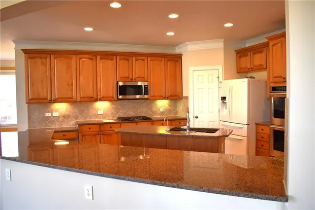 a kitchen with stainless steel appliances granite countertop a refrigerator and a stove