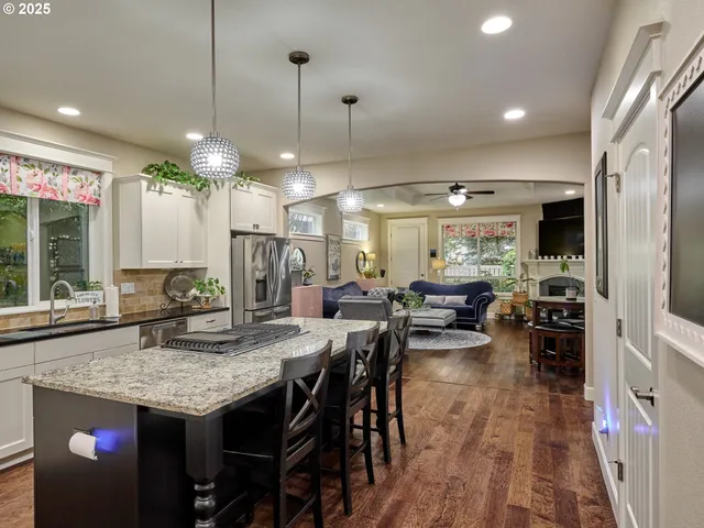 a kitchen with stainless steel appliances kitchen island granite countertop a table chairs sink and cabinets