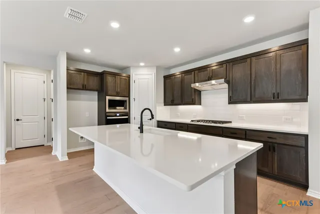 a large kitchen with stainless steel appliances granite countertop a sink a stove and a refrigerator