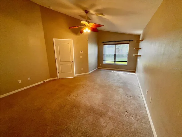 a view of an empty room with a window and a kitchen