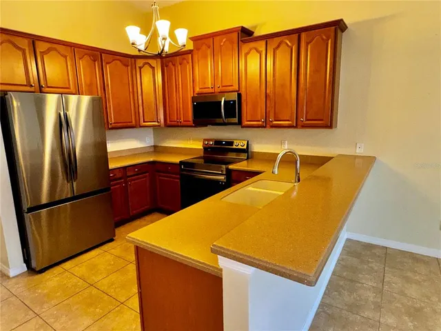 a kitchen with stainless steel appliances granite countertop a refrigerator a stove top oven and a sink