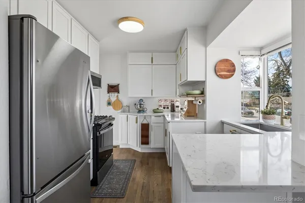 a kitchen with stainless steel appliances granite countertop a refrigerator a stove and a sink with large window