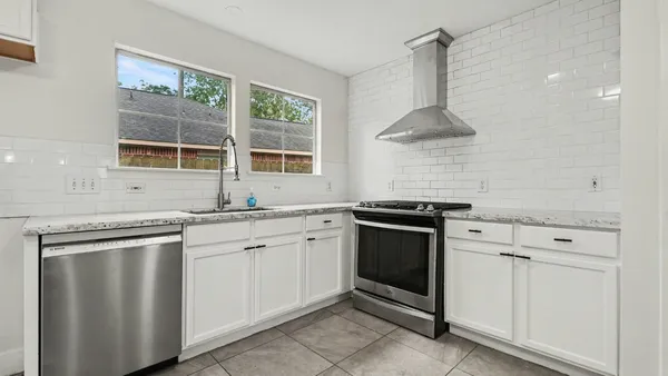 a kitchen with stainless steel appliances granite countertop white cabinets a sink and a stove