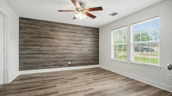 a view of empty room with wooden floor and fan