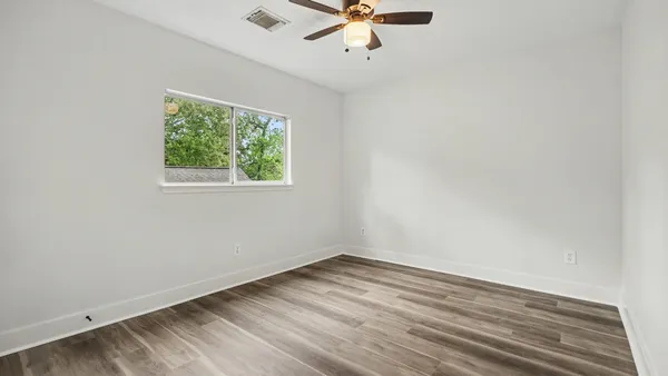 an empty room with a window and a fan