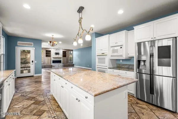 a large kitchen with kitchen island a large counter top and stainless steel appliances