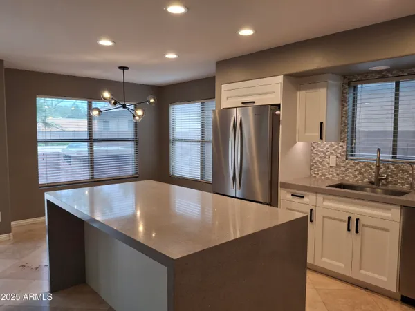 a large kitchen with kitchen island a large counter top and stainless steel appliances
