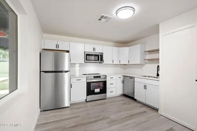 a kitchen with cabinets stainless steel appliances and wooden floor