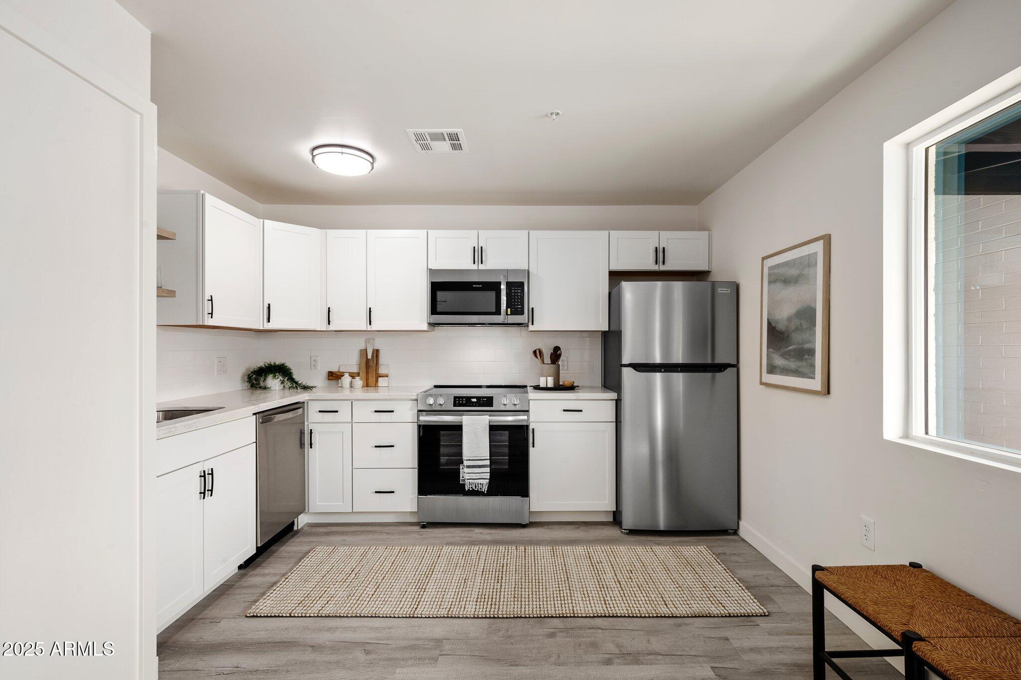 3114 North 68th Street, Unit 3 Scottsdale, AZ 85251 - Photo 3 of 25 a kitchen with stainless steel appliances granite countertop a stove top oven a refrigerator a sink and dishwasher with white cabinets