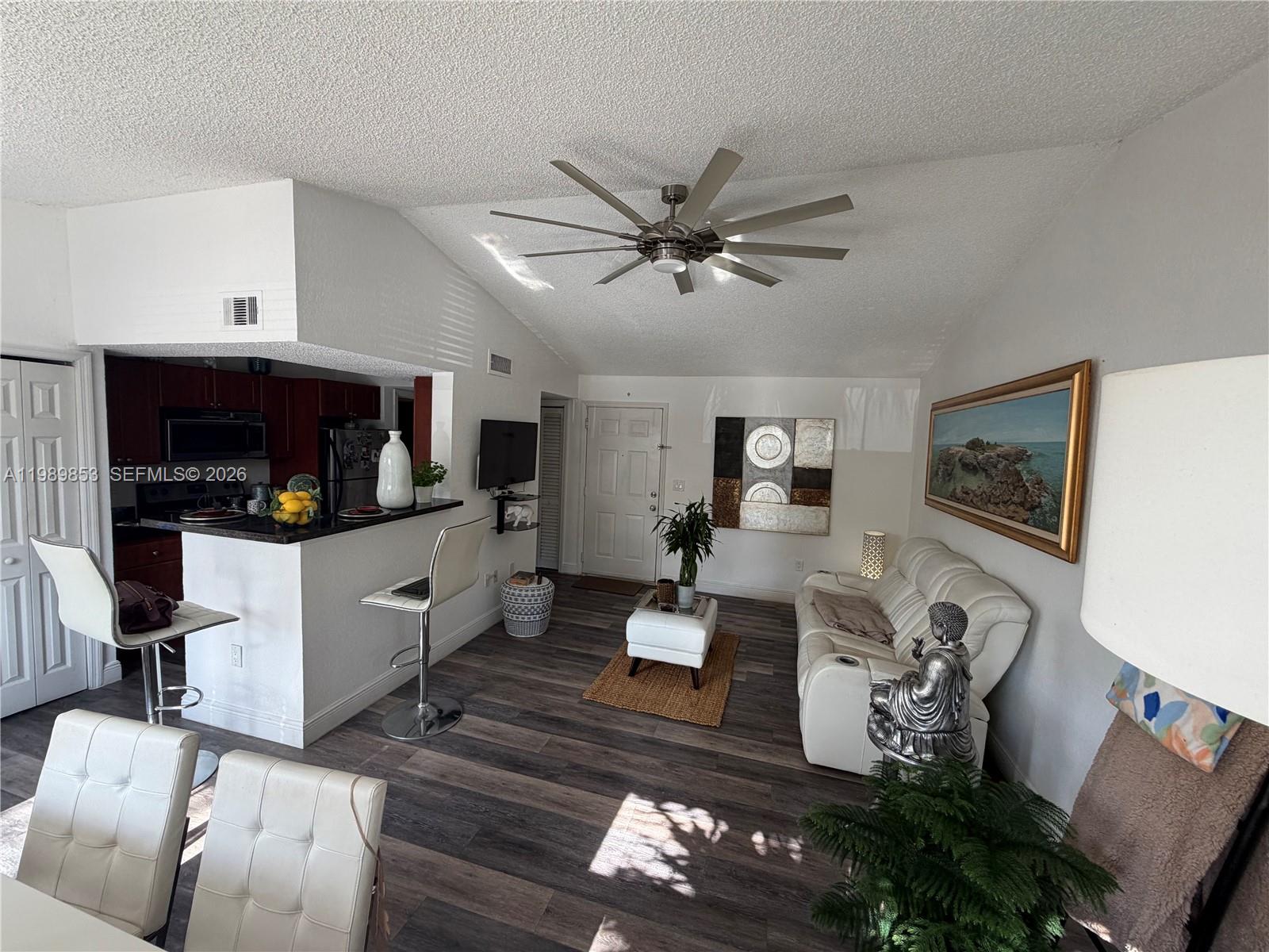 10670 Southwest 156th Place, Unit 308 Miami, FL 33196 - Photo 1 of 21 a living room with furniture and a flat screen tv with kitchen view