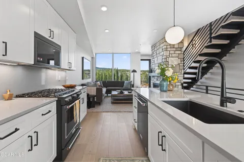 a kitchen with stainless steel appliances a sink stove and white cabinets with wooden floor