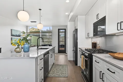 a kitchen with stainless steel appliances granite countertop a sink a stove and a wooden floors