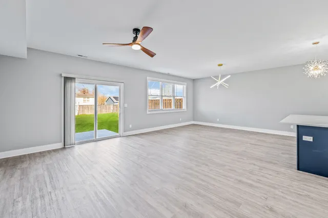 a view of an empty room with window wooden floor and a kitchen
