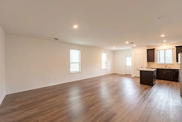 a kitchen with stainless steel appliances granite countertop a stove top oven a sink dishwasher a refrigerator and a oven with wooden floor