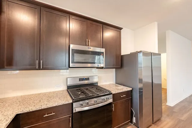 a kitchen with kitchen island a counter top space cabinets and stainless steel appliances