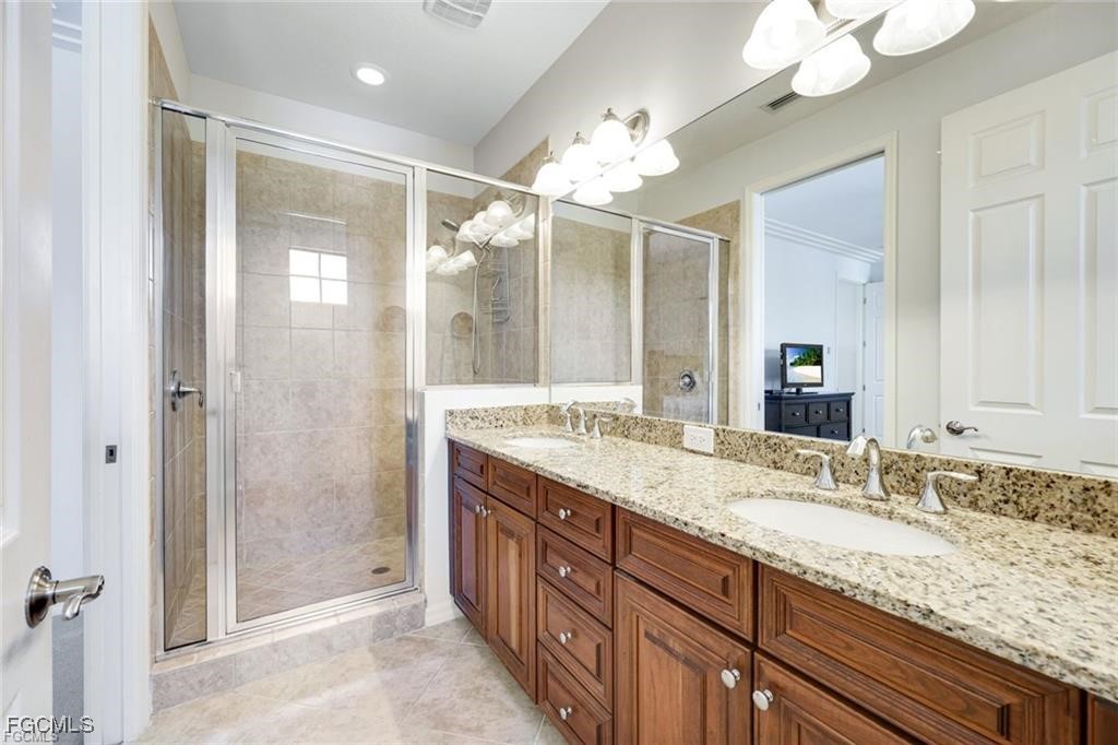 11758 Izarra Way, Unit 7703 Fort Myers, FL 33912 - Photo 12 of 37 a bathroom with a granite countertop double vanity sink mirror and shower