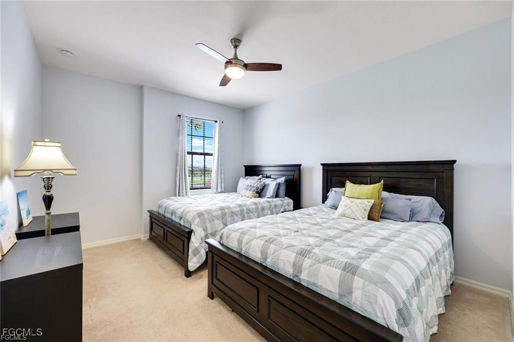 11758 Izarra Way, Unit 7703 Fort Myers, FL 33912 - Photo 14 of 37 a bedroom with two beds and a lamp on a dresser