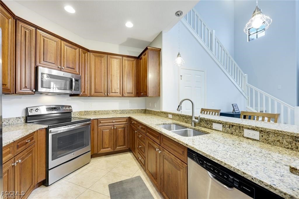 11758 Izarra Way, Unit 7703 Fort Myers, FL 33912 - Photo 6 of 37 a kitchen with stainless steel appliances granite countertop a sink dishwasher stove and oven with wooden cabinets