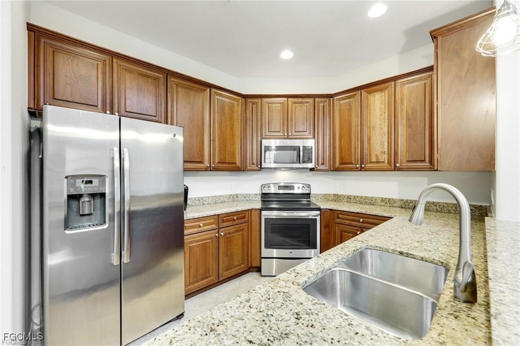 11758 Izarra Way, Unit 7703 Fort Myers, FL 33912 - Photo 8 of 37 a kitchen with granite countertop a refrigerator sink and stove