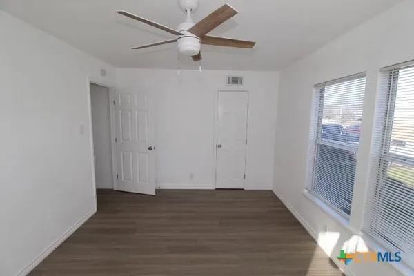 an empty room with wooden floor and windows