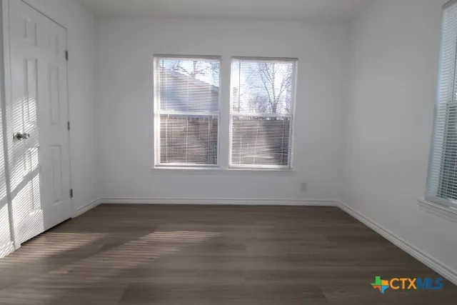 a view of an empty room with wooden floor and a window