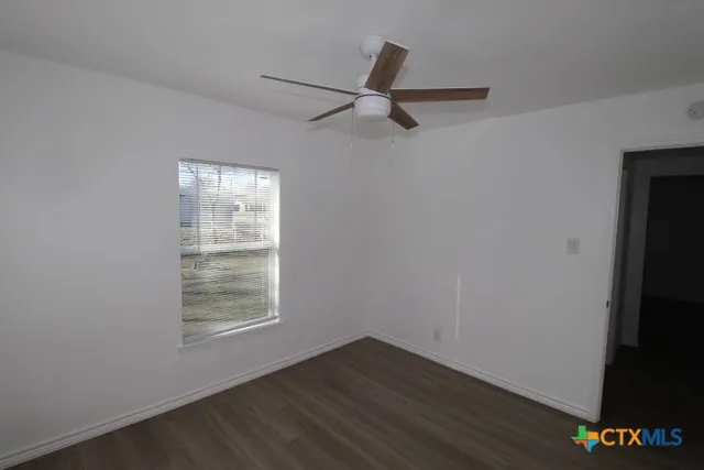 an empty room with wooden floor closet and windows