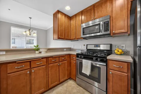 a kitchen with stainless steel appliances granite countertop a stove a microwave oven a sink dishwasher and cabinets with wooden floor