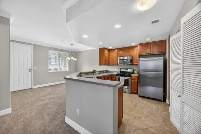 a kitchen with granite countertop a refrigerator oven a sink dishwasher and wooden cabinets