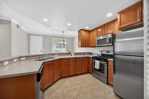 a kitchen with stainless steel appliances granite countertop a sink stove refrigerator and cabinets