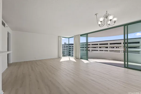 an empty room with wooden floor staircase and a kitchen