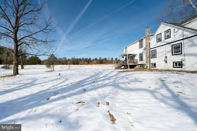 a view of an empty room with wooden floor fire place and a window