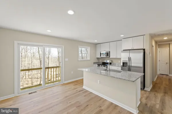 a large kitchen with kitchen island a large counter top space a sink stainless steel appliances and cabinets