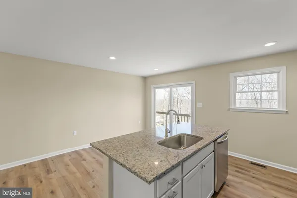a kitchen with granite countertop a sink and dishwasher with wooden floor
