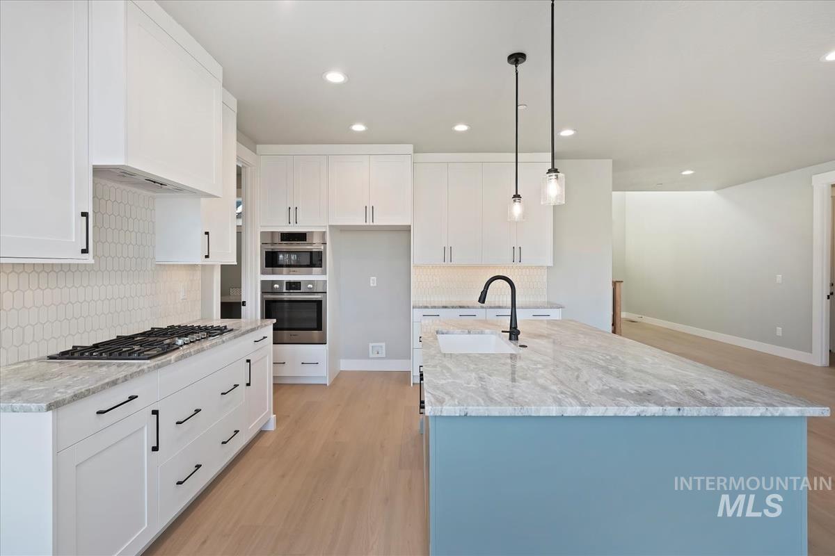 404 Hidden Mill Middleton, ID 83644 - Photo 12 of 41 Kitchen featuring white cabinets, pendant lighting, a kitchen island with sink, light stone countertops, and light wood finished floors