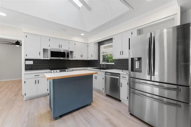a kitchen with kitchen island granite countertop white cabinets and stainless steel appliances