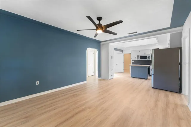 a view of a kitchen with a refrigerator a ceiling fan and wooden floor