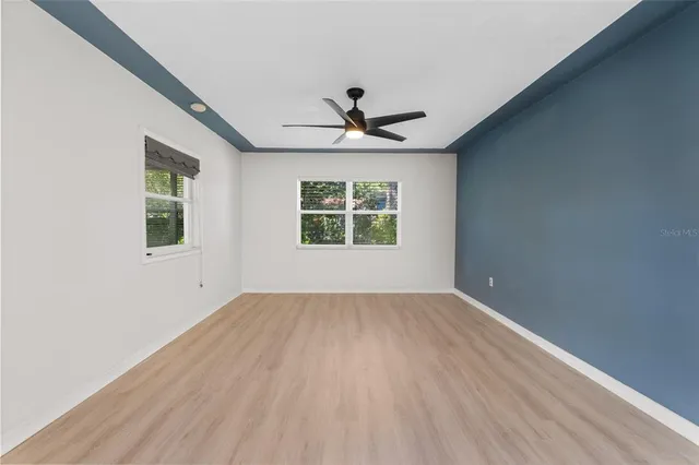 an empty room with windows and chandelier fan