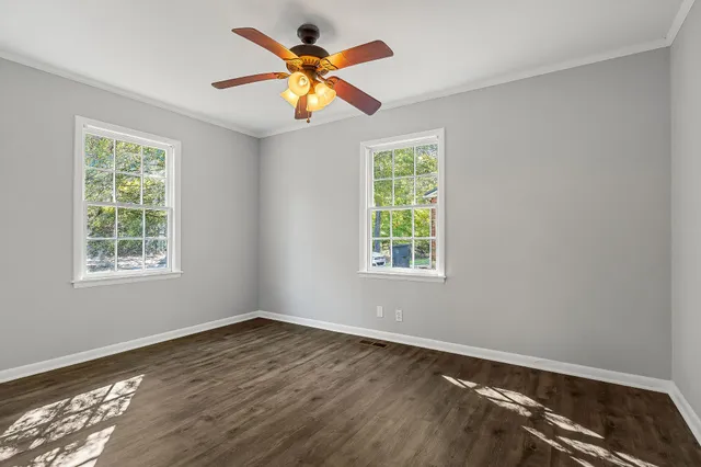an empty room with wooden floor and windows