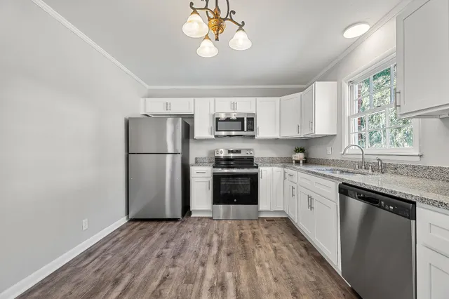 a kitchen with granite countertop a refrigerator a stove a sink and dishwasher with wooden floor