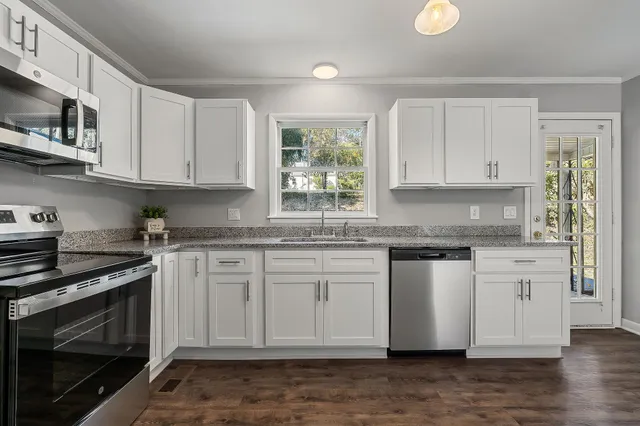 a kitchen with stainless steel appliances granite countertop a stove a sink and a microwave