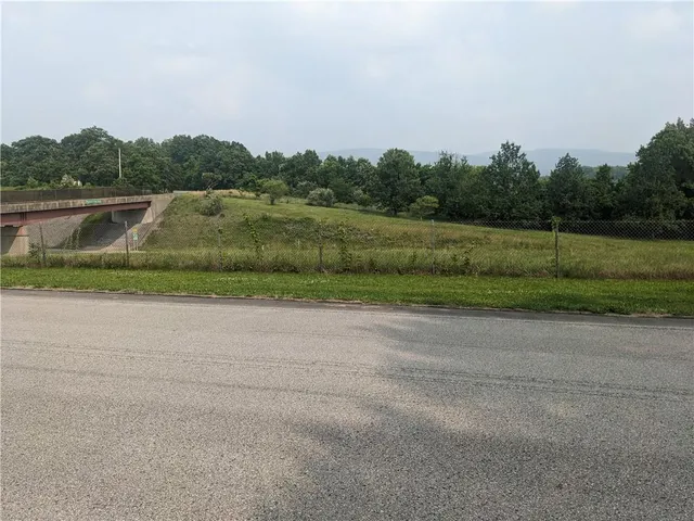 a view of a green field with trees in the background
