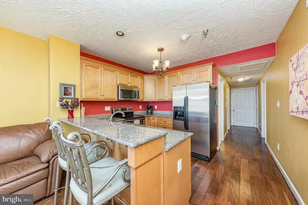 a kitchen with stainless steel appliances granite countertop a refrigerator a oven a sink with island and chairs
