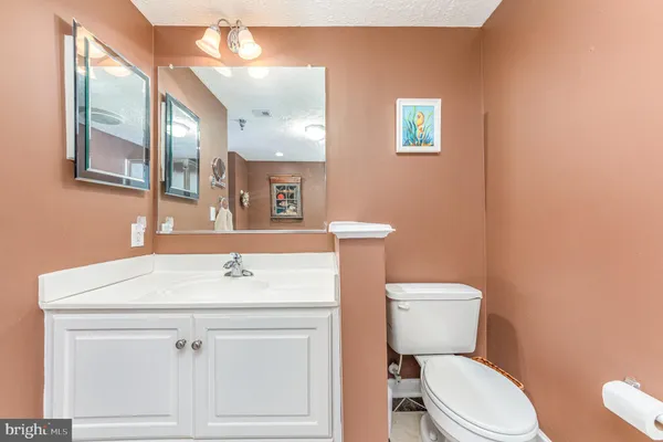 a bathroom with a toilet sink vanity and mirror