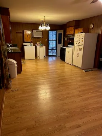 a view of a kitchen with kitchen island a counter top space a sink a stove and wooden cabinets