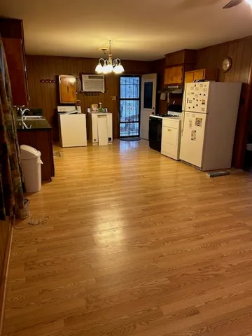 a view of a kitchen with kitchen island a counter top space a sink a stove and wooden cabinets