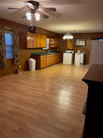 a large kitchen with stainless steel appliances kitchen island granite countertop a refrigerator a stove a sink a dining table and chairs with wooden floor