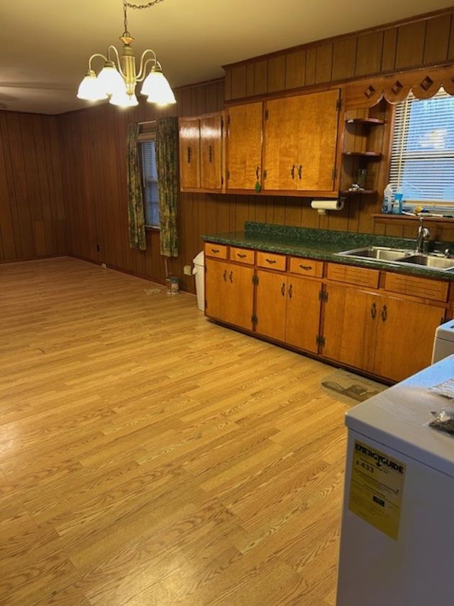 7030 Asbury Glimp Road Ripley, TN 38063 - Photo 15 of 22 Kitchen with brown cabinetry, light wood finished floors, dark countertops, wooden walls, and hanging light fixtures